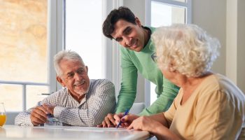 Young,Man,Helps,Seniors,With,Dementia,Solve,Puzzles,As,Memory