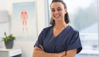 Portrait,Of,Happy,Female,Caucasian,Physiotherapist,Wearing,Scrubs,At,Hospital.