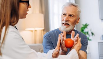Female,Doctor,Providing,Hand,Exercise,With,A,Therapy,Ball,To