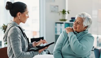 Old,Woman,,Physiotherapist,And,Tablet,With,Shoulder,Pain,At,Clinic
